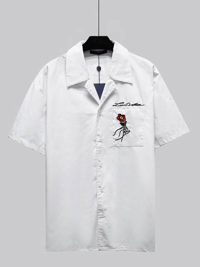 新款 这款白色棉质短袖衬衫采用开放式保龄球领设计，是对 Ss24 秀场巴黎的艺术致敬。创意细节包括背面的 Lv Pont Neuf 刺绣、衣领后面对比鲜明的“M