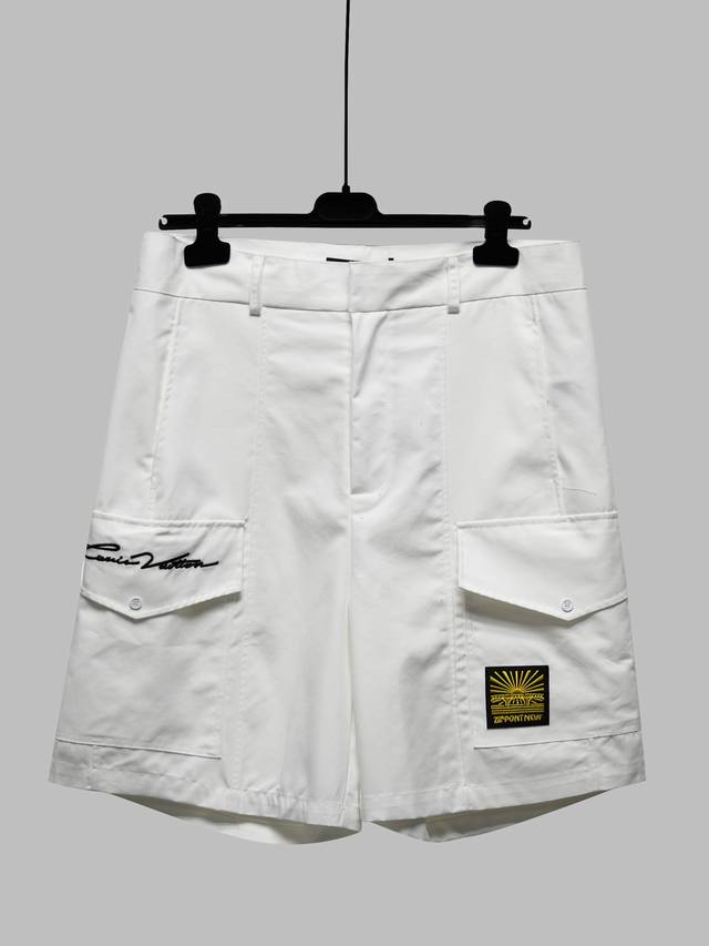 新款 这款纯白色棉质工装短裤是一款百搭的跨季节单品。两侧有两个纽扣贴袋，上面绣有 1Ouis Vuitton 标志和 1V Pont Neuf 标志贴袋。它们既